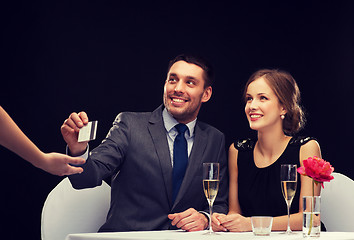 Image showing smiling couple paying for dinner with credit card