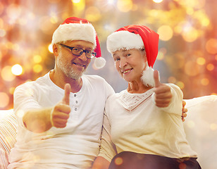 Image showing senior couple in santa hats showing thumbs up