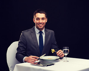 Image showing smiling man with tablet pc eating main course