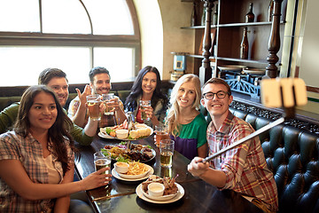 Image showing happy friends with selfie stick at bar or pub