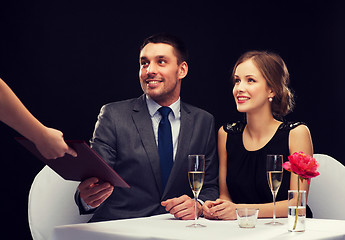 Image showing waiter giving menu to happy couple at restaurant