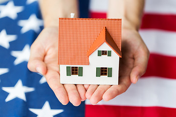 Image showing close up of hands holding house over american flag