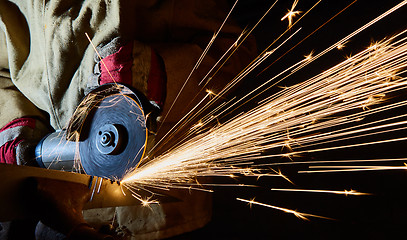 Image showing Worker cutting metal with grinder. Sparks while grinding iron