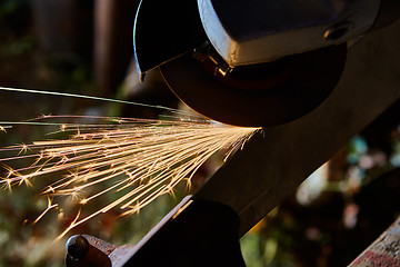 Image showing Worker cutting metal with grinder. Sparks while grinding iron