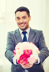 Image showing smiling handsome man giving bouquet of flowers