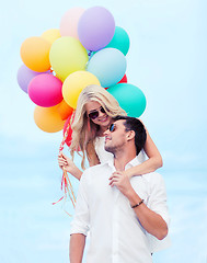 Image showing couple with colorful balloons at seaside