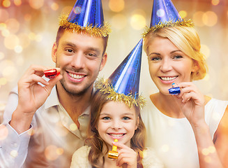 Image showing smiling family in blue hats blowing favor horns