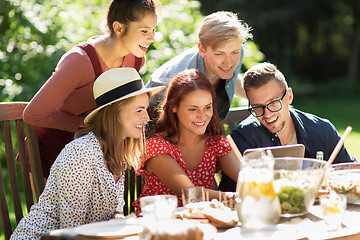 Image showing friends with tablet pc at dinner in summer garden