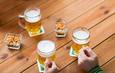 Image showing close up of hands with beer mugs at bar or pub