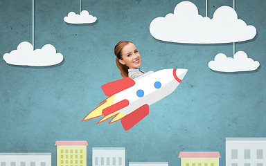 Image showing businesswoman flying on rocket above cartoon city