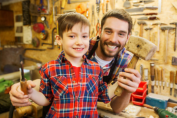 Image showing boy with dad holding chisel and hammer at workshop