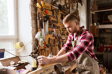 Image showing carpenter working with plane and wood at workshop