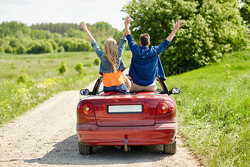 Image showing happy friends driving in cabriolet car at country