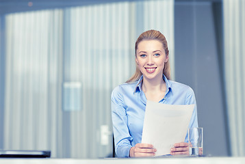 Image showing smiling woman holding papers in office