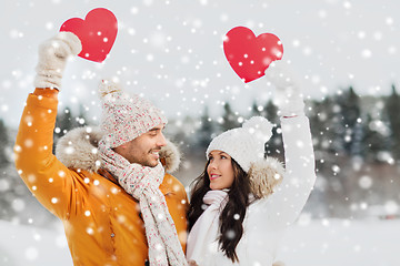 Image showing happy couple with red hearts over winter landscape