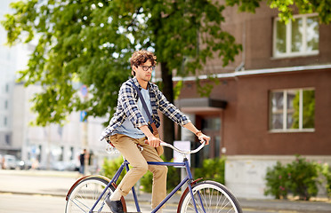 Image showing young hipster man with bag riding fixed gear bike