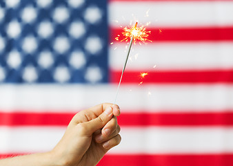 Image showing close up of hand with sparkler over american flag