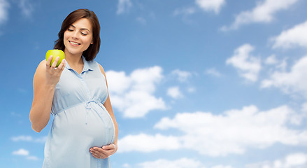Image showing happy pregnant woman looking at green apple
