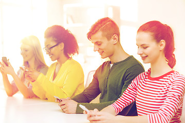 Image showing four smiling students with smartphones at school