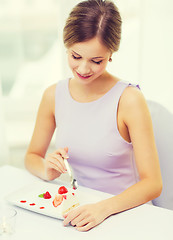 Image showing smiling young woman eating dessert at restaurant