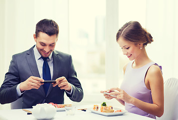 Image showing smiling couple with sushi and smartphones