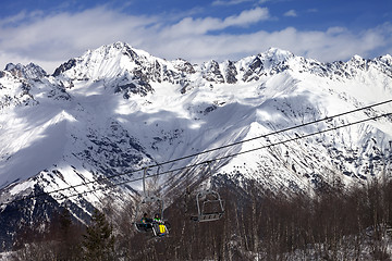 Image showing Skiers on ski-lift at winter sun day