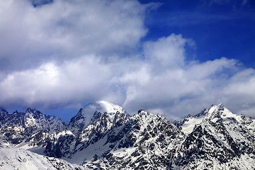 Image showing Snow mountaims in clouds at sun winter day