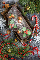 Image showing Cake Christmas log, candy, tree branches and a garland.