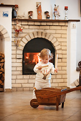 Image showing The little girl standing at home against fireplace