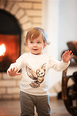 Image showing Happy child little girl standing at home against fireplace