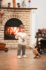 Image showing Happy child little girl standing at home against fireplace