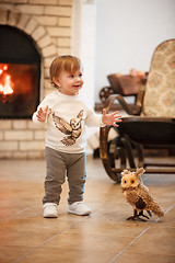 Image showing Happy child little girl standing at home against fireplace