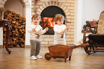 Image showing The two little girls standing at home against fireplace