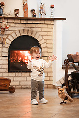 Image showing Happy child little girl standing at home against fireplace