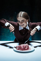 Image showing Bloody Halloween theme: crazy girl with a knife, fork and meat