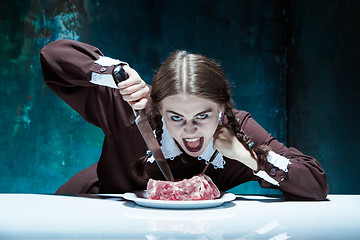 Image showing Bloody Halloween theme: crazy girl with a knife, fork and meat