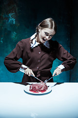 Image showing Bloody Halloween theme: crazy girl with a knife, fork and meat