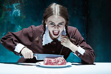 Image showing Bloody Halloween theme: crazy girl with a knife, fork and meat