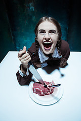 Image showing Bloody Halloween theme: crazy girl with a knife, fork and meat