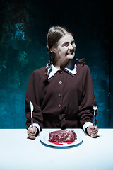 Image showing Bloody Halloween theme: crazy girl with a knife, fork and meat