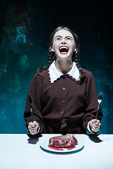 Image showing Bloody Halloween theme: crazy girl with a knife, fork and meat