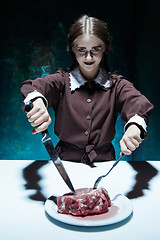 Image showing Bloody Halloween theme: crazy girl with a knife, fork and meat