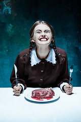 Image showing Bloody Halloween theme: crazy girl with a knife, fork and meat