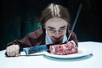 Image showing Bloody Halloween theme: crazy girl with a knife, fork and meat