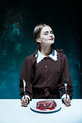 Image showing Bloody Halloween theme: crazy girl with a knife, fork and meat