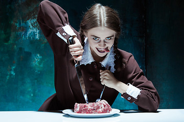 Image showing Bloody Halloween theme: crazy girl with a knife, fork and meat