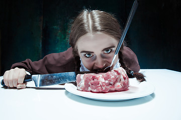 Image showing Bloody Halloween theme: crazy girl with a knife, fork and meat