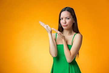 Image showing The thinking Chinese girl on yellow background