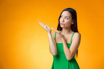 Image showing The thinking Chinese girl on yellow background