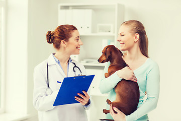 Image showing happy woman with dog and doctor at vet clinic